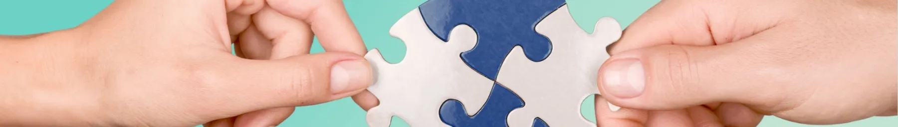 Jigsaw puzzle pieces being put together and held by two hands